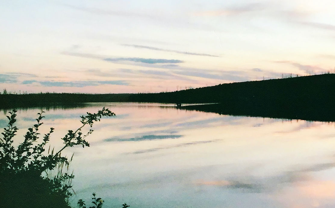 A pink sunset over a lake, the sky reflected in the water.