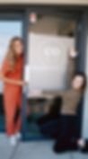 A photograph of Stephanie standing and Alex kneeling in front of the co-valley co-working door. The co-valley logo is visible on the door.