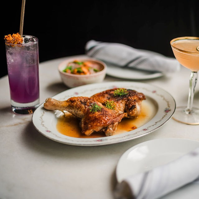 Roasted chicken dish with cocktails and appetizers on a white table.