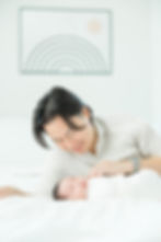 Newborn photographers Philadelphia - melissa joy photography - new dad lies on bed wearing cream shirt while newborn baby sleeps on bed next to him