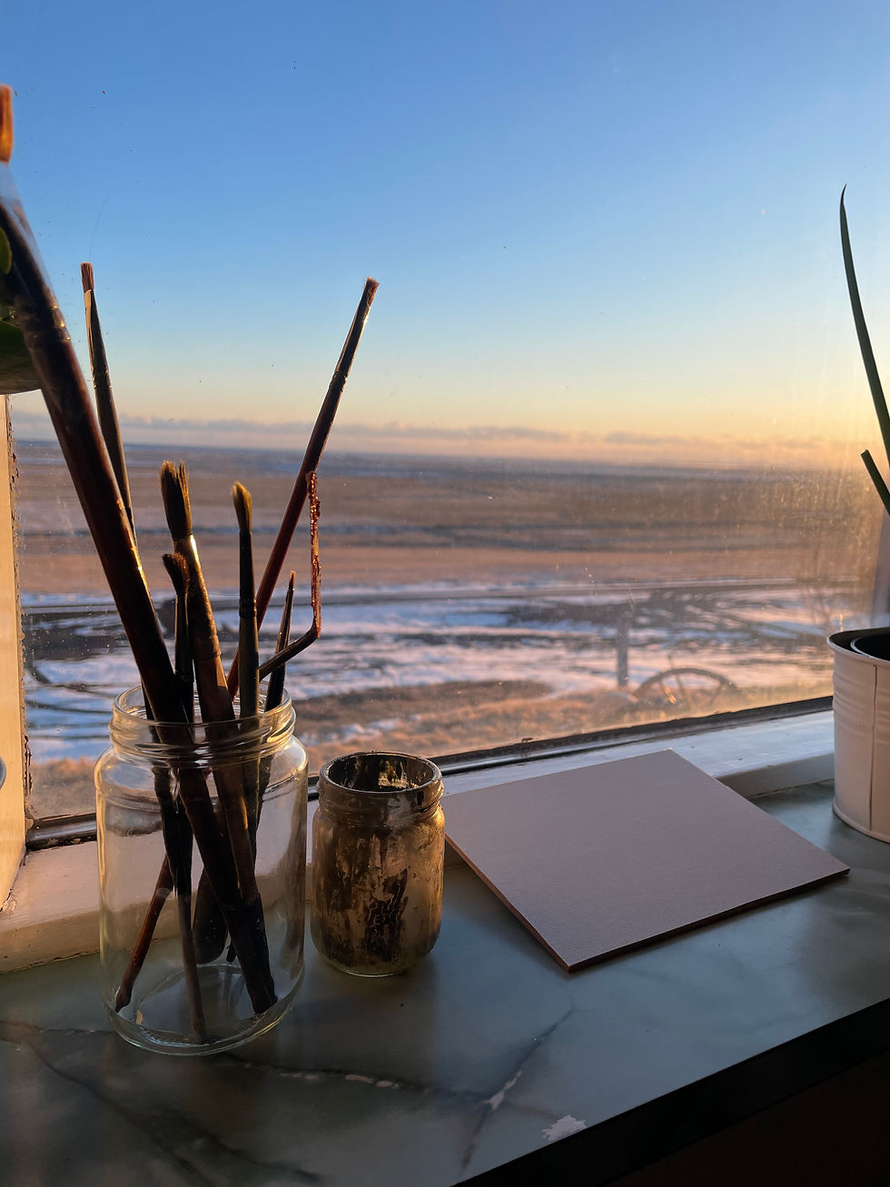 Islandzki krajobraz widoczny przez okno, na pierwszym planie puste płótno i pędzle