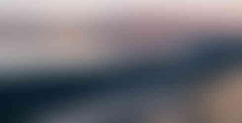 Zatoka z czarnym piaskiem i pomarańczowym światłem na szczytach gór