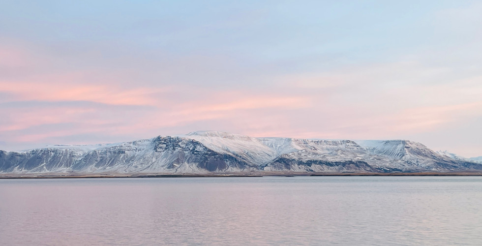Morze, w tle płaskie ośnieżone góry, różowe niebo