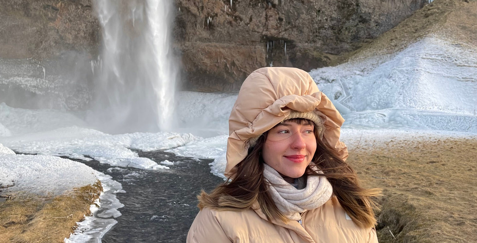 Kobieta w puchowej kurtce na tle wodospadu