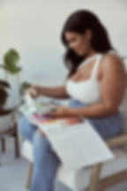 Taylor Long sitting on a chair reviewing swimwear fabric swatches.