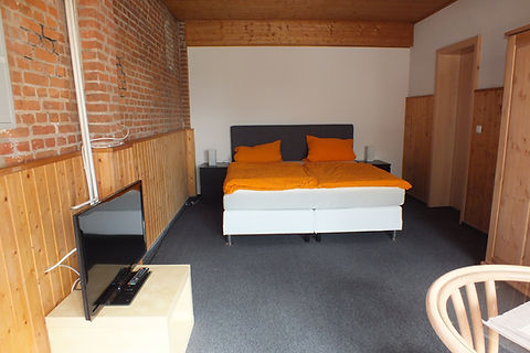 Doppelbett mit orangefarbener Bettwäsche im Zimmer Caprimond