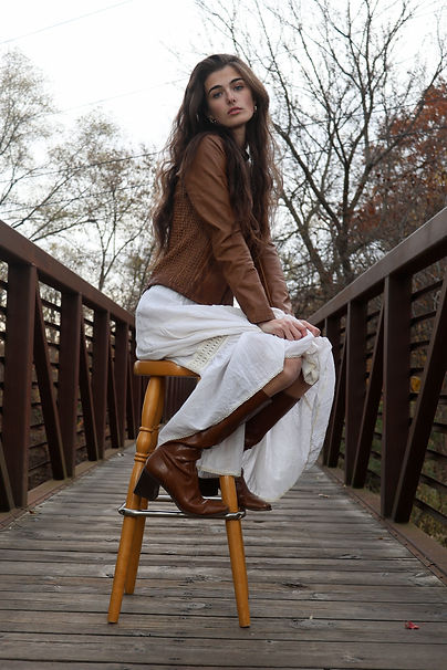 Central Michigan University senior Raina Abbott poses on a bridge looking off into the distance at Island Park, Thursday, November 6, 2025. Despite cool temperatures, Abbott took time out of her birthday day for the photoshoot. Camera settings: f/4.5, ISO 200, 1/125sec, 32mm lens. Flash settings: A1/32, B1/16