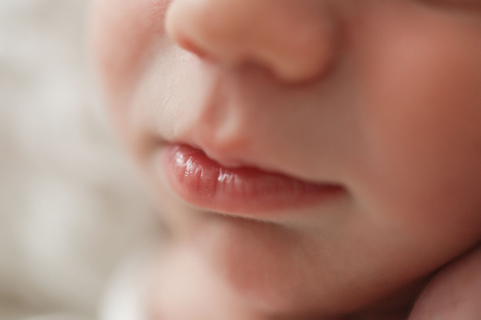 Close-up of a baby's lips and nose, soft lighting highlighting the gentle texture and natural blush of the skin. Warm and serene mood.