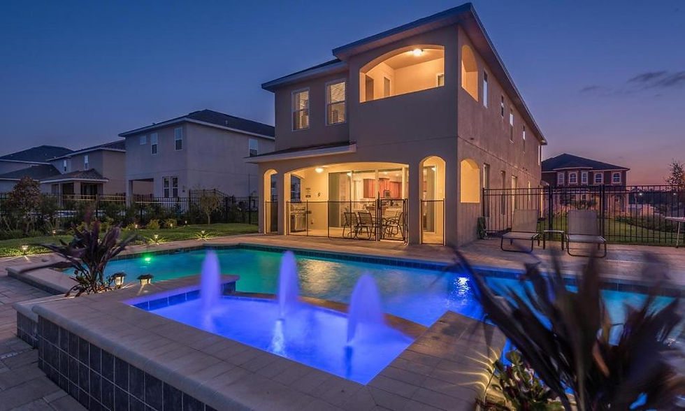 Two‑story home with a covered patio and illuminated swimming pool at dusk.