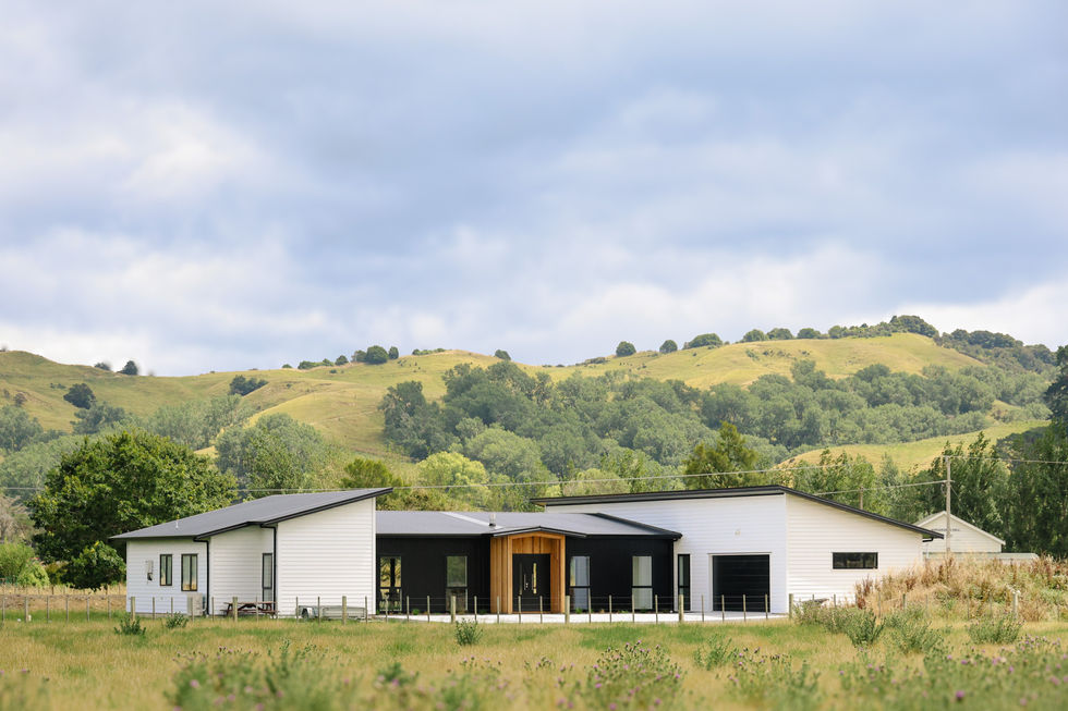 Exterior photo of a large new monopitched black and white home with accents of cedar.