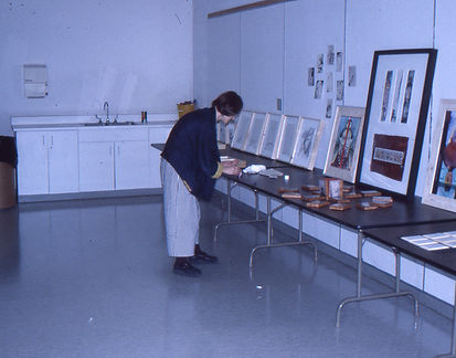 A series of professionally framed artworks laid out flat across a large studio table, viewed while being carefully reviewed and inspected before transport.