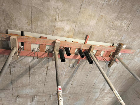 Baugerüst mit schwarzen Rohren, Holzkonstruktion an einer Beton Decke, Detailaufnahme.