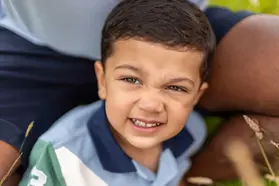 Close-up photo of a young child looking directly at the camera with a cute, expressive face, capturing innocence, charm, and playful personality for social media and family photography.