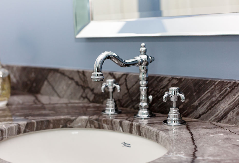 Chrome faucet on marble vanity with white sink