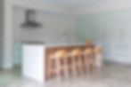 Modern kitchen with island, stools, and light green cabinets