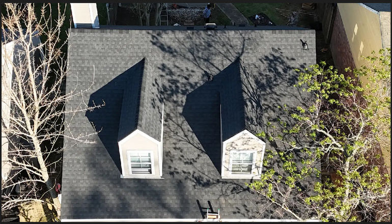 Aerial view of two dormer windows on a grey shingle roof
