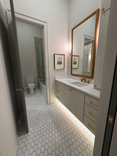 Modern bathroom vanity with a gold-framed mirror and hexagonal tile floor