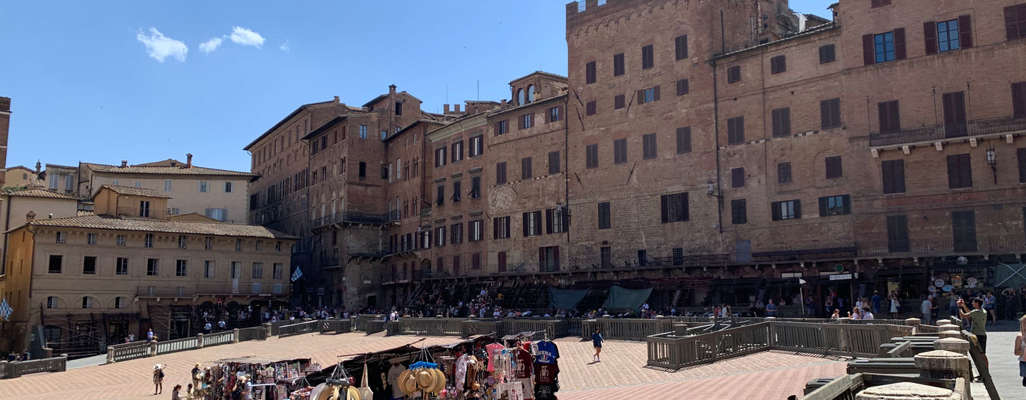 Piazza del Campo, Siena, Italy, with shops and buildings against blue sky