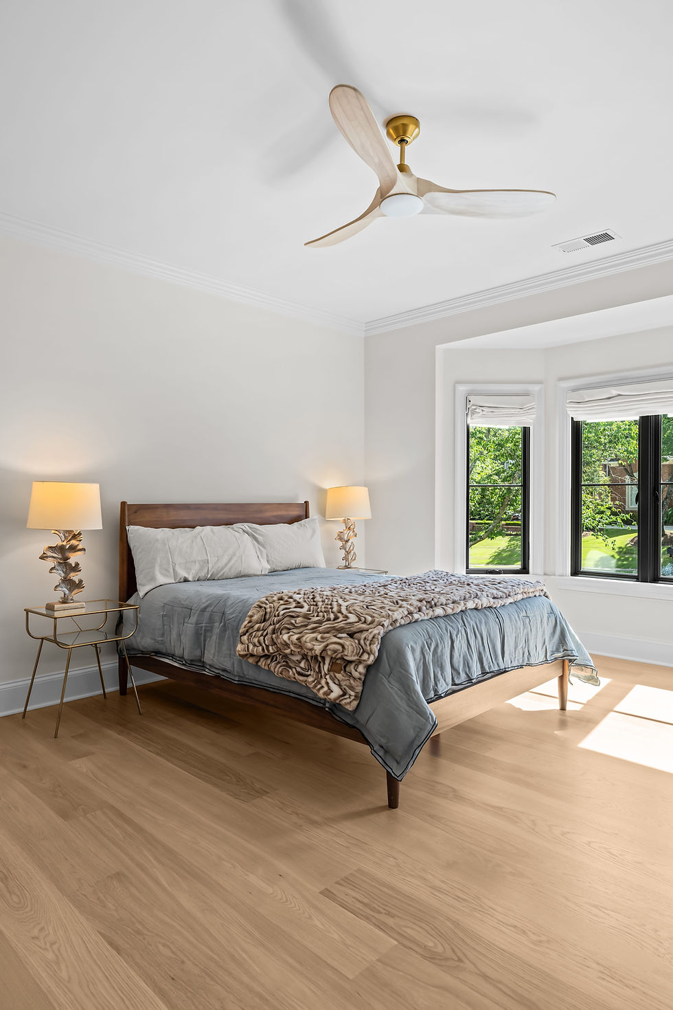Modern bedroom with light hardwood flooring and ceiling fan.