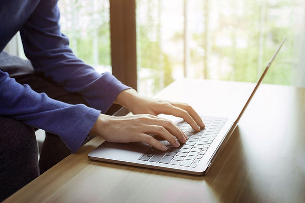 Person typing on laptop, hands visible, working with technology, writing email.