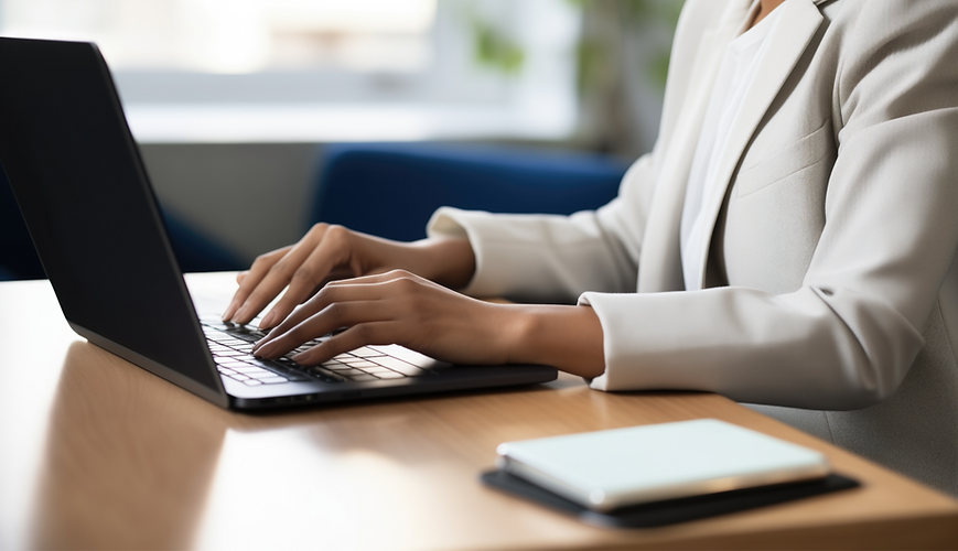 Woman typing on laptop at desk, working in office environment.