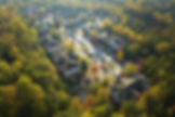 Aerial view of apartments surrounded by trees and parked cars.