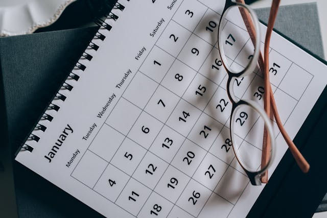 A calendar of the month of January with glasses sitting on top.