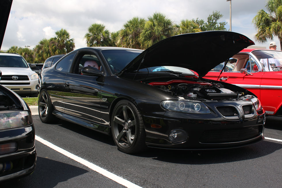 Black Pontiac GTO with the hood up at a car show