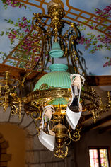 editorial styled photo of the brides shoes hanging from light fixture inside the chateau noland located in san luis obispo, ca