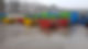 Colourful industrial waste containers lined up on a wet concrete surface