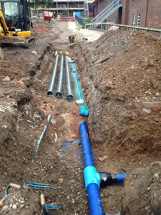 Blue water pipes laid in a deep earth trench on a construction site