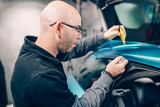 A person applying a wrap to a car's hood