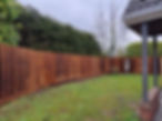 A wooden fence encloses a grassy backyard with a football