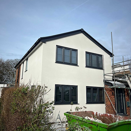 Recently rendered house with new windows and a skip in front