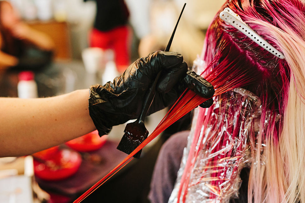 Hairdresser applying dye to strands of hair wrapped in foil