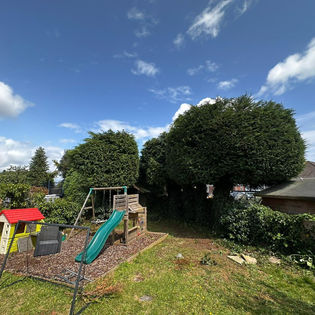 A garden with a play area featuring a slide and playhouse