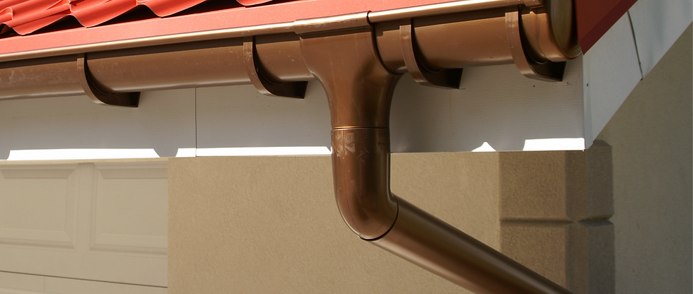 Close up of clean brown plastic guttering installed below modern red roof tiles