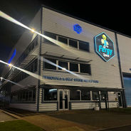 Exterior view of a large commercial storage building illuminated by spotlights at night