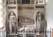 An ancient tomb with sculpted figures and a reclining effigy