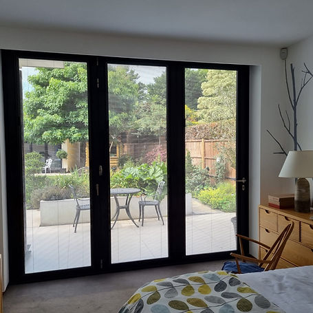 Modern bedroom with large glass doors opening to a lush garden