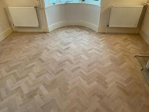 Room with herringbone-patterned wooden floor and two white radiators