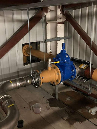 Large blue industrial valve connected to steel pipework inside a utility building