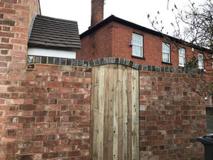 A wooden gate set in a brick wall