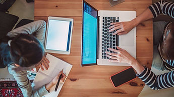 A person's hand using a laptop on a wooden desk