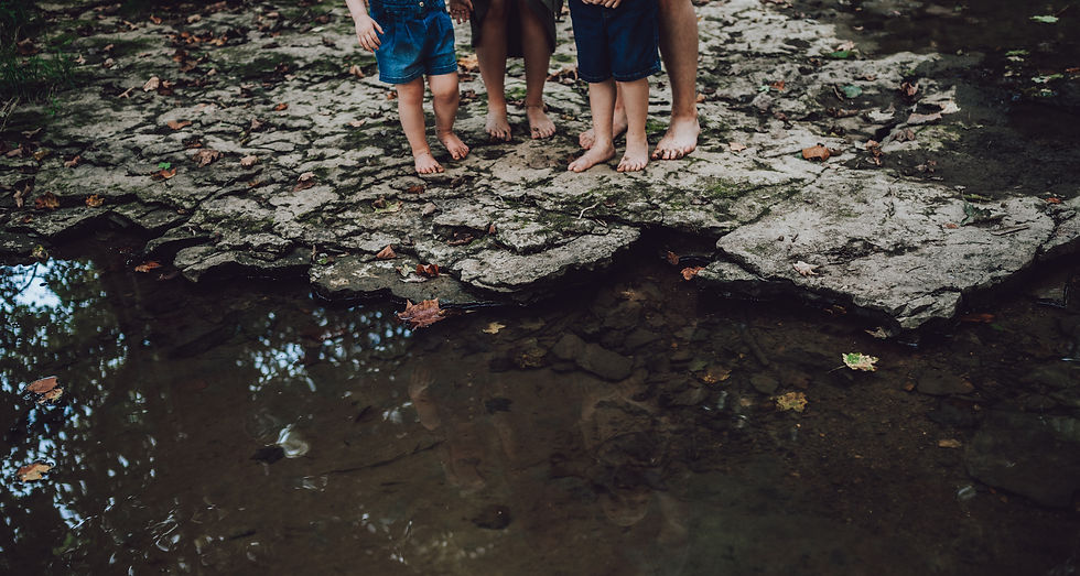 Family photo of family standing in a creek focused on their feet on rock bed in Lexington Indiana by Jessie Silakowski Photography