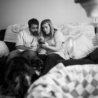 family relaxing with newborn and family dog during in-home lifestyle newborn photography session