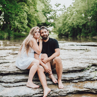 Couple sitting on rocks in creek during Madison Indiana Engagement photoshoot