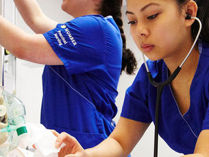 Estudante de Enfermagem Prática do Humber Polytechnic praticando habilidades práticas em um ambiente de laboratório simulado de cuidados de saúde.