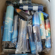 Rolled up mouse pads with various designs in a cardboard box