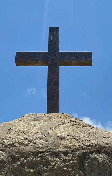 A cross stands on a rock with the sun’s flare shining upon it_edited.jpg